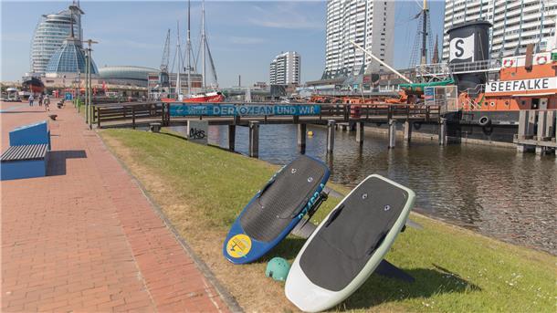 eHydrofoil-Surfen in Bremerhaven: Mein erster Flug über Wasser Zwei Surfbretter stehen am Rand des alten Hafenbeckens