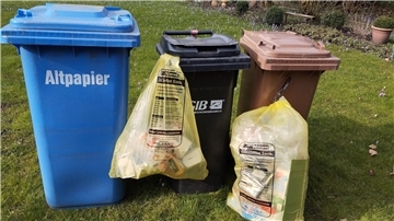 Gelber Sack neben blauer, schwarzer und brauner Tonne