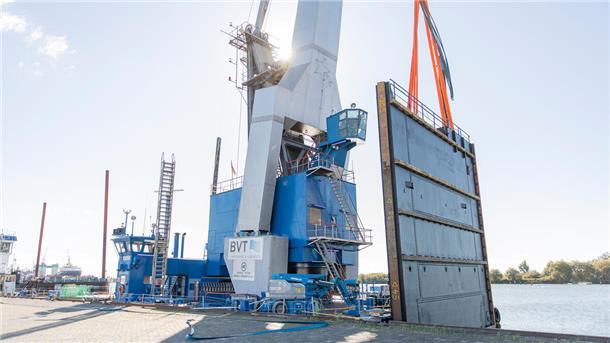Das gigantische Sperrwerk steht bereit für den Transport – aufgerichtet auf dem Kran „Athlet“ an der Kaje im Fischereihafen.
