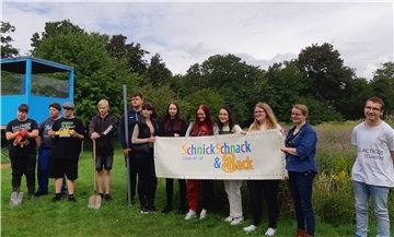 Eine Gruppe von Menschen und ein Banner mit dem Logo der Schülerfirma