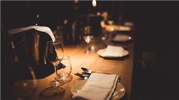 Ein gedeckter Tisch bei schummerigen Licht. Das Universum lädt regelmäßig zum Dinner im Dunkeln ein und führt die Gäste in eine fremde Welt.
