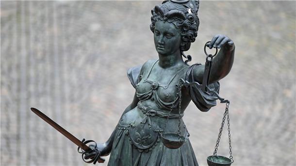 Eine Statue der Justitia hält eine Waage und ein Schwert in der Hand