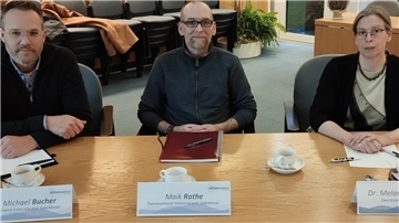 Zwei Männer und eine Frau an einem Tisch.