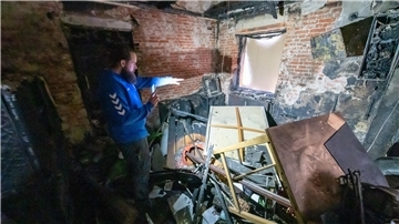 Mann leuchtet mit Handy in zerstörten Raum. 