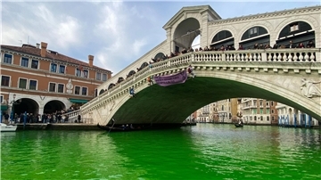Das Wasser des Canal Grande unter der Rialto-Brücke in Venedig ist leuchtend grün gefärbt.