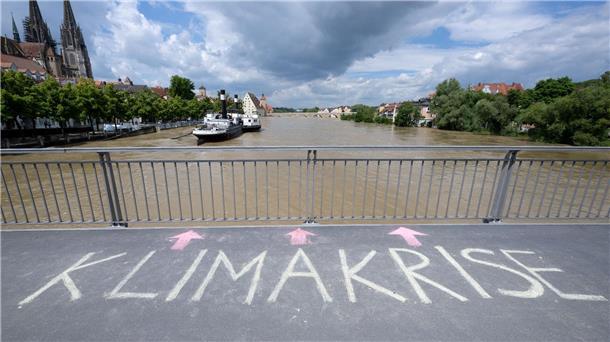 Das Wort „Klimakrise“ ist auf einer Brücke über der Donau in Regensburg zu lesen.