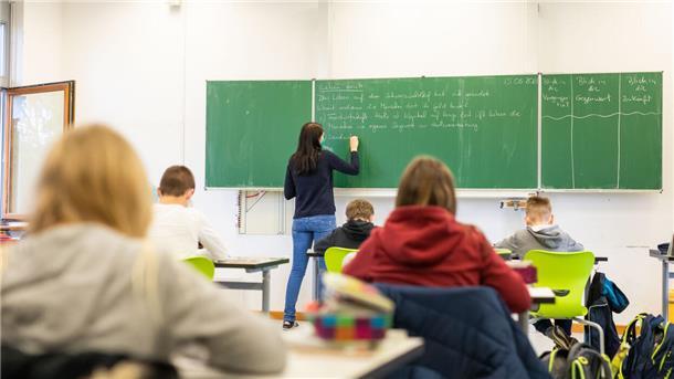 Schülerinnen und Schüler einer fünften Klasse sitzen während des Unterrichts in ihrem Klassenzimmer