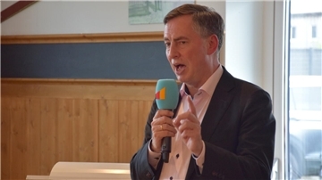 Ein Mann im Anzug hält eine Rede. 