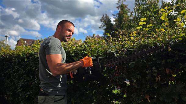 Ein junger Mann mit einer Heckenschere.