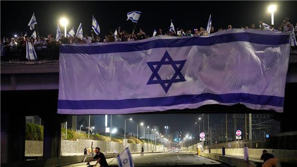 Demonstranten haben bei ihren Protesten eine riesige Nationalfahne an einer Autobahnüberführung in Tel Aviv aufgehängt.