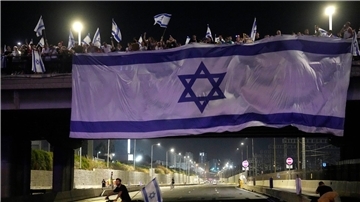 Demonstranten haben bei ihren Protesten eine riesige Nationalfahne an einer Autobahnüberführung in Tel Aviv aufgehängt.