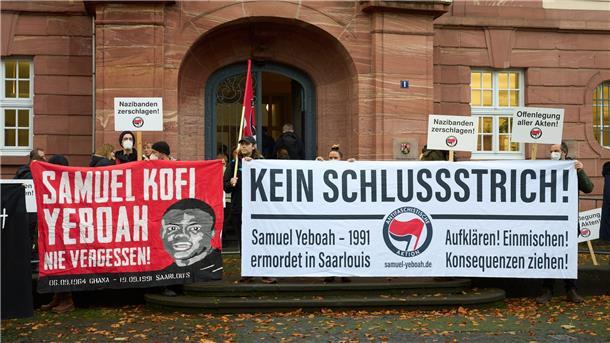 Demonstranten stehen vor dem Prozessbeginn am Eingang des Oberlandesgerichts.