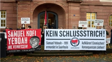 Demonstranten stehen vor dem Prozessbeginn am Eingang des Oberlandesgerichts.