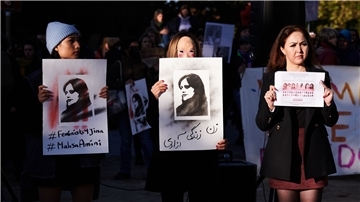 Demonstrantinnen halten in Berlin Schilder in die Höhe, auf der die im Iran getötete Kurdin Jina Mahsa Amini zu sehen ist.