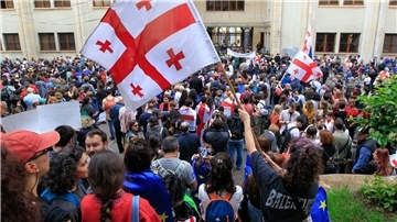Demonstrantinnen und Demonstranten schwenken vor dem Parlamentsgebäude in Tiflis georgische Nationalflaggen.