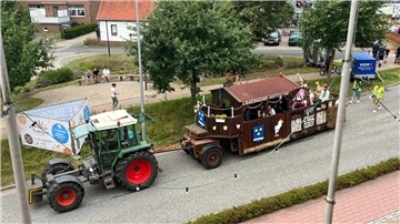 Ein geschmückter Erntewagen wird von einem Trecker gezogen.