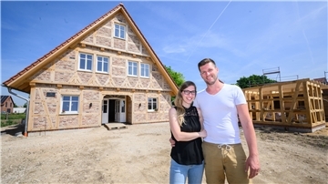 Denise und Thiemo Merz stehen vor ihrem neuen Fachwerkhaus in einem Neubaugebiet in Sehnde-Rethmar in der Region Hannover.