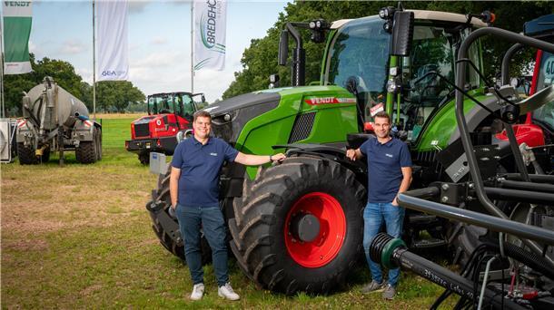 Melkautomaten und GPS-gesteuerte Schlepper: Sie bringen digitale Technik auf den Acker Zwei Männer stehen am Vorderreifen eines großen grünen Schleppers