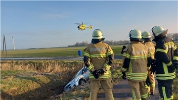 Unfall in Butjadingen: Im Hintergrund ist ein Rettungshubschrauber zu sehen, im Vordergrund Feuerwehrleute.