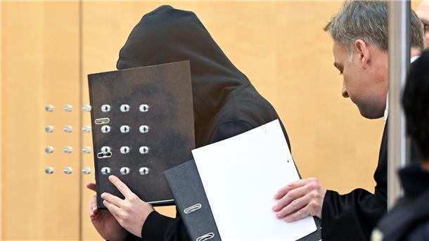 Rechter Bombenbau im Kinderzimmer: Gymnasiast vor Gericht Der Angeklagte (l) verdeckt mit einem Aktenordner sein Gesicht, als er mit seinem Verteidiger zu Beginn der Verhandlung in einem Saal am Oberlandesgericht eintrifft.