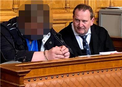Zwi iMänner sitzen auf der Anklagebank in einem Gerichtssaal. 