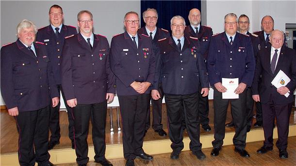 Der ausgeschiedene Kreisbrandmeister Heiko Basshusen und sein Nachfolger Ralf Hoyer ehrten Thomas Hülsebusch, Heinz Bielefeld, Jens Cordes, Uwe Menke, Stefan Hobbie, Thomas Luerssen, Bernd Kempendorf, Klaus Braje und Günter Busch (von links). Foto: Flor
