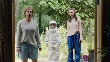 Zwei Frauen und ein kleiner Junge stehen in einer Tür. Der Junge ist als Astronaut verkleidet.