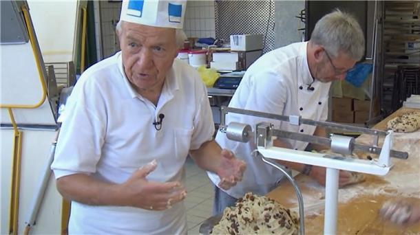 Ein Bäcker steht am Tisch und wiegt Teig ab.