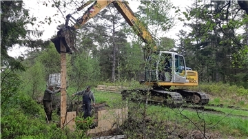 Der Bagger drückt behutsam die Bohlen in den weichen Grund. Das Staubauwerk im Holzurburger Forst nimmt Form an. Es soll dafür sorgen, dass das Moor immer ausreichend gewässert ist.
