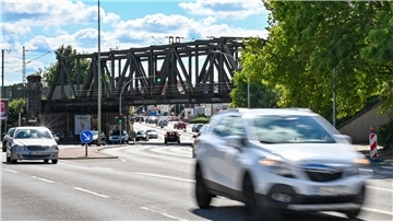 Eisenbahnbrücke über Straße, im Vordergrund Autos.