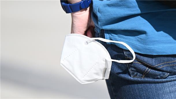 Ein Mann trägt eine Maske in der Hand.