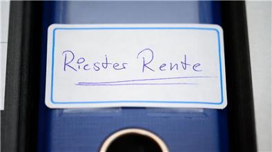 Ein blauer Ordner mit der Aufschrift "Riester-Rente" steht in einem Regal. Die Banken verlangen von Kunden Kosten, die vom Bundesgerichtshof untersagt worden sind. 