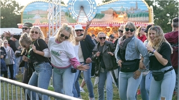 Menschen tanzen vor einer Bühne auf einer Open-Air-Party.
