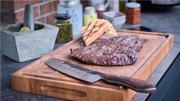 Der „Deichgriller“ nimmt das Steak vom Grill und legt es gemeinsam mit dem krossen Brot auf ein Holzbrett. Dort soll es etwa fünf Minuten lang ruhen. Wenn er es direkt anschneiden würde, könnte zu viel kostbarer Fleischsaft austreten.