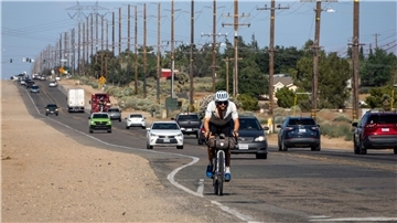 Der deutsche Athlet Jonas Deichmann fährt mit seinem Fahrrad eine Straße in den USA entlang.