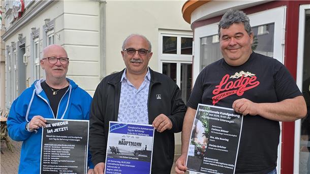 Film „Der Hauptmann“ in Brake: Gedenken und Kino vereint Männer stehen zusammen. Sie halten Plakate in den Händen. Dahinter ist das Centralkino Brake zu sehen.