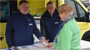 Der ehrenamtliche Mitarbeiter Arno Mittelmeyer (links) und Dr. Matthias Ahlbrecht (mitte) erhalten eine Wasserprobe von einem Brunnennutzer überreicht.