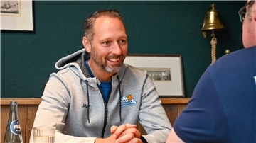 Ein Basketball-Trainer lacht, während er ein Interview gibt. Es ist Steven Esterkamp von den Eisbären Bremerhaven.