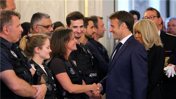 Der französische Präsident Emmanuel Macron und seine Frau Brigitte Macron (r) treffen in Annecy Rettungskräfte.