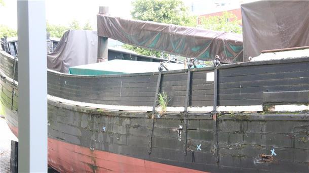 Ein altes Holzschiff, das an Land ausgestellt wird.