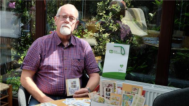 Ein Mann sitzt im Garten mit Briefmarken.