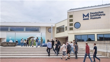 Menschen gehen auf Gebäude zu. 