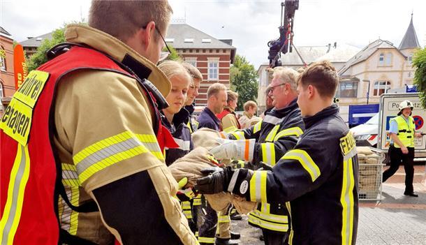 Hochwasserschutztag in Brake: Feuerwehrleute schleppen Sandsäcke.