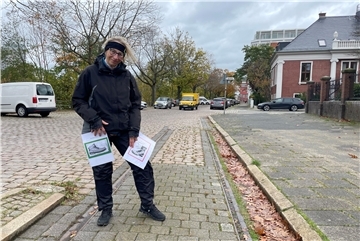 Roter Stinkstiefel für die Kaistraße: Bremerhavenerin für Veränderung Eine Frau, die auf einer Straße steht. Sie hält zwei Zettel in den Händen. Darauf sind jeweils Stiefel zu sehen, einmal rot und einmal grün umrandet.