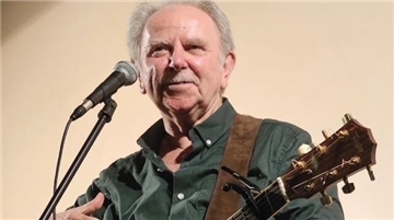 Ein Mann mit Gitarre am Mikrofon.