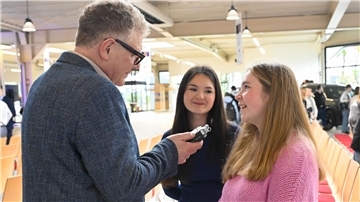 Ein älterer Mann und zwei junge Frauen im Gespräch.