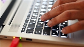 Jemand tippt etwas auf der Tastatur eines Laptops.