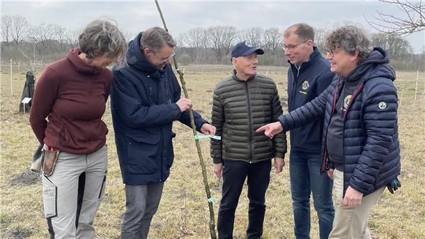 Am Rande einer Streuobstwiese werden Obstbäume gepflanzt. Dahinter steht eine Aktion des Zevener Lions Club.