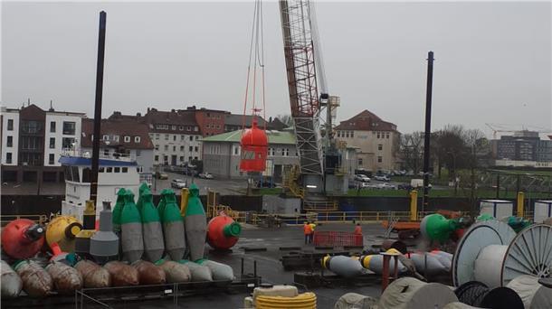 Wohin die Kuppel des Molenturms verschifft wurde Der Molenturm-Kopf hängt am Haken: Der Bord-Kran des Arbeitsschiffes hebt die Kuppel vom Tonnenhof-Gelände auf das Schiff.
