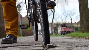 Ein Mann steht mit seinem Rad vor einer Stolperfalle im Radweg.